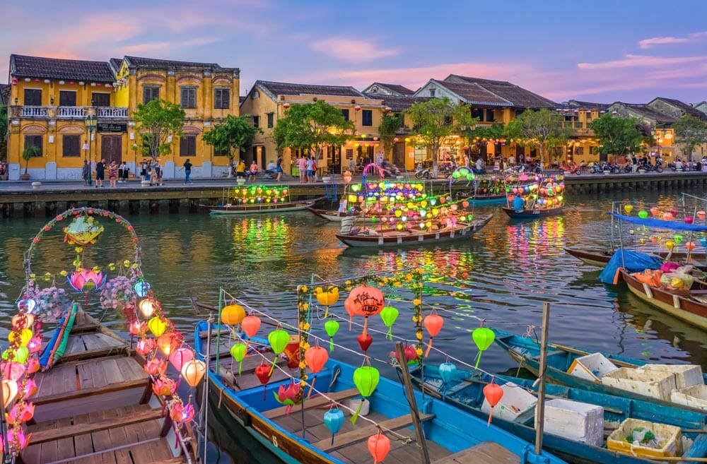barcos en el río de Hoi An rodeados de farolillos y edificios coloniales amarillos
